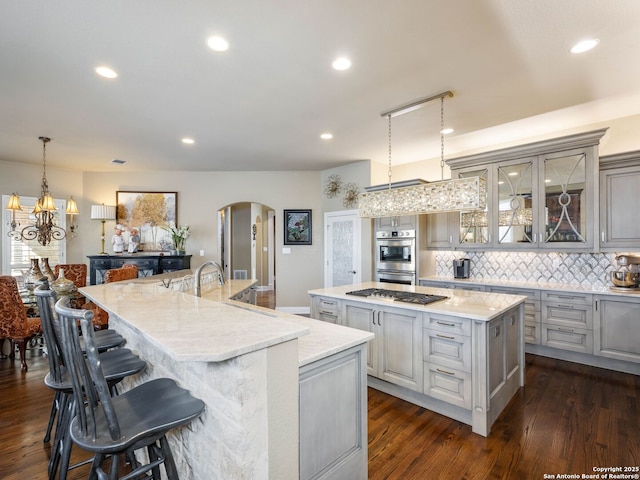 kitchen featuring decorative light fixtures, gray cabinetry, decorative backsplash, stainless steel appliances, and a spacious island