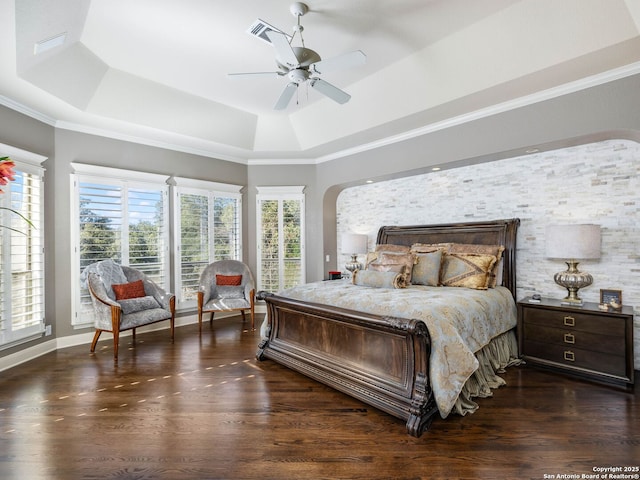 bedroom featuring dark wood-type flooring, ceiling fan, ornamental molding, and a tray ceiling