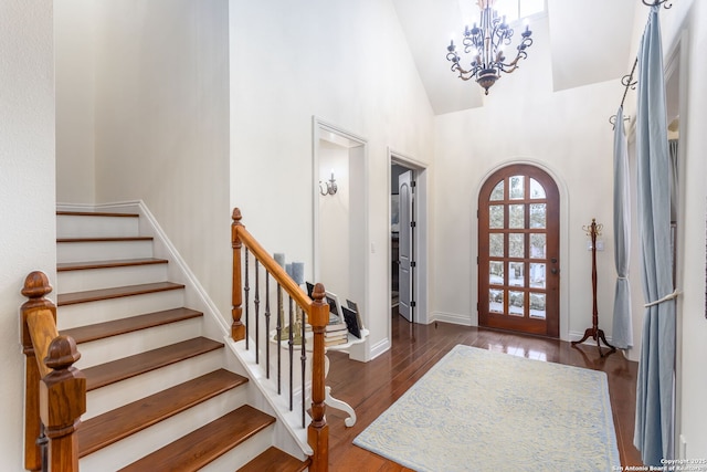 entrance foyer featuring dark wood-type flooring, a chandelier, and high vaulted ceiling