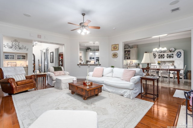 living room featuring ceiling fan with notable chandelier, wood-type flooring, and ornamental molding