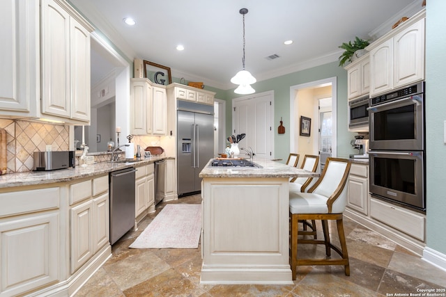 kitchen featuring appliances with stainless steel finishes, pendant lighting, a breakfast bar area, a center island, and light stone counters