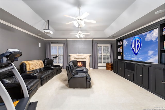 home theater with carpet flooring, a high end fireplace, a tray ceiling, and ornamental molding