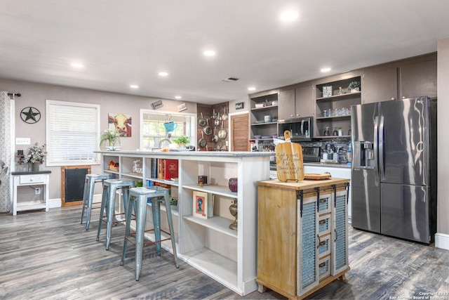 kitchen with dark wood-type flooring, stainless steel appliances, and a breakfast bar