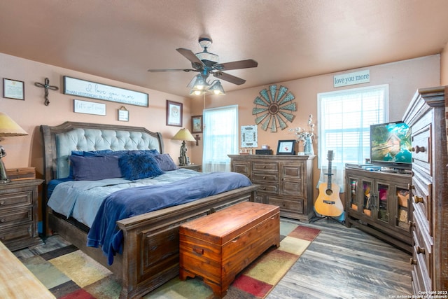 bedroom with hardwood / wood-style flooring, ceiling fan, multiple windows, and a textured ceiling