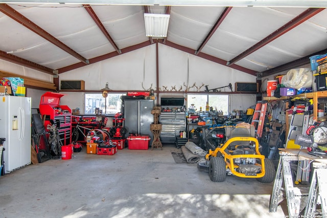 garage featuring a workshop area and white fridge with ice dispenser