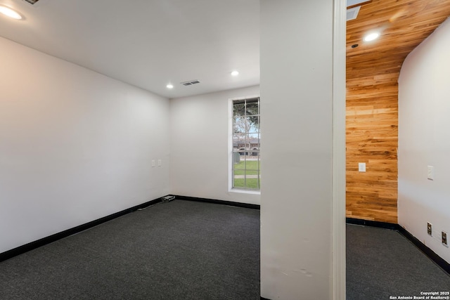 spare room with dark carpet and wooden walls