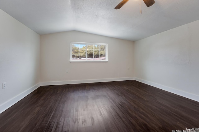 spare room with ceiling fan, vaulted ceiling, dark hardwood / wood-style floors, and a textured ceiling