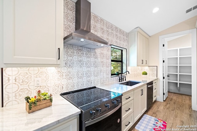 kitchen with sink, white cabinetry, range with electric stovetop, light stone countertops, and wall chimney range hood