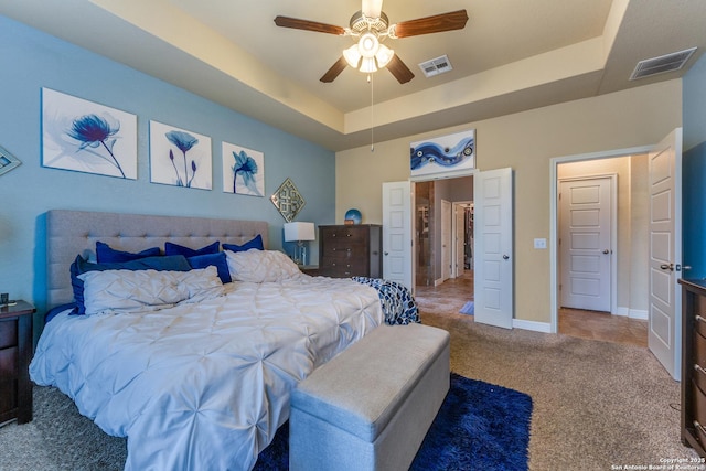 carpeted bedroom featuring a tray ceiling and ceiling fan