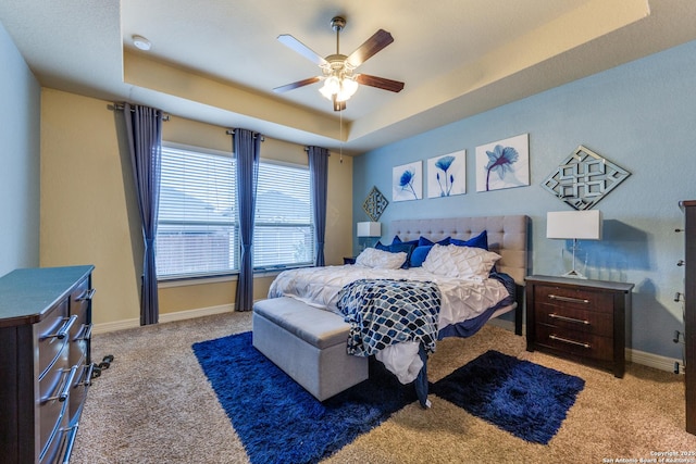 bedroom with light colored carpet, ceiling fan, and a tray ceiling