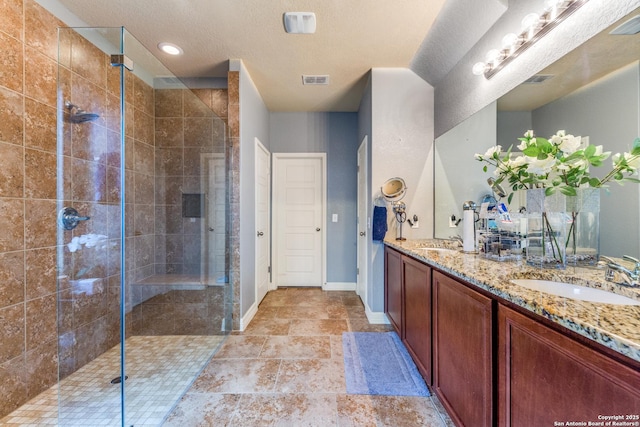 bathroom with vanity, a textured ceiling, and tiled shower