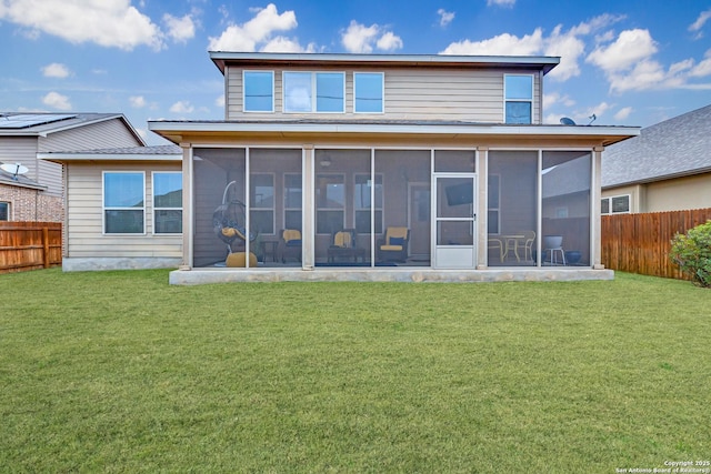 rear view of property featuring a yard and a sunroom