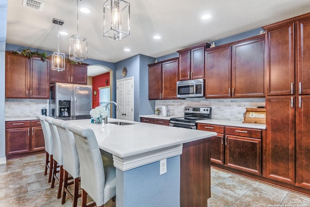 kitchen featuring sink, a kitchen bar, hanging light fixtures, a kitchen island with sink, and stainless steel appliances