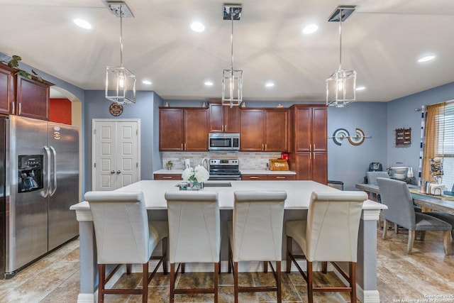 kitchen featuring a kitchen island, stainless steel appliances, a kitchen bar, and hanging light fixtures