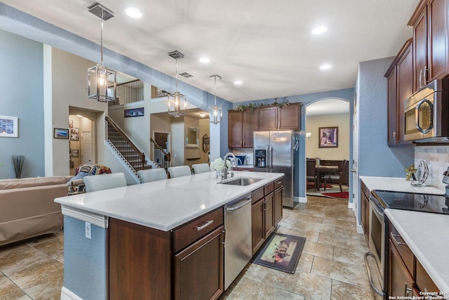 kitchen featuring pendant lighting, sink, appliances with stainless steel finishes, a kitchen island with sink, and a kitchen breakfast bar