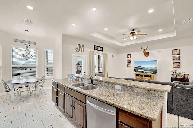 kitchen featuring sink, a kitchen island with sink, hanging light fixtures, a tray ceiling, and stainless steel dishwasher