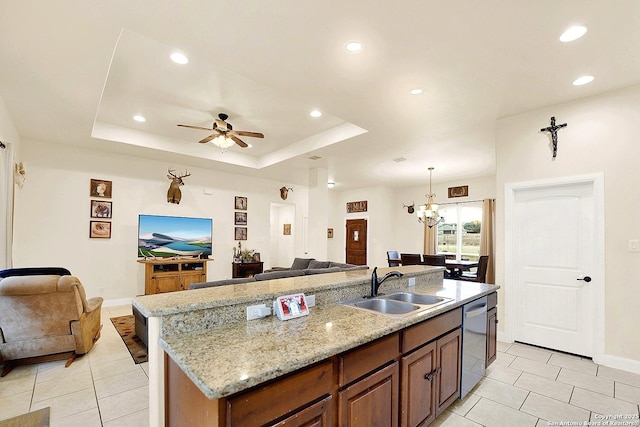 kitchen with pendant lighting, sink, dishwasher, a kitchen island with sink, and light stone countertops