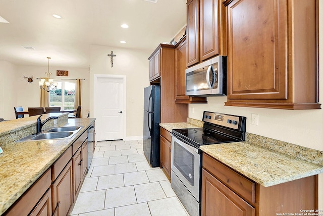 kitchen featuring pendant lighting, sink, appliances with stainless steel finishes, light stone counters, and a chandelier