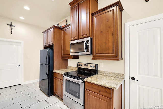 kitchen featuring light stone counters, stainless steel appliances, and light tile patterned floors