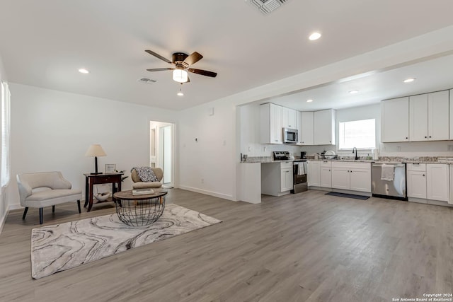 living room with ceiling fan, sink, and light wood-type flooring