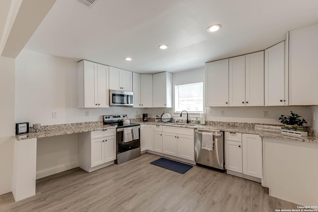 kitchen featuring stainless steel appliances, white cabinets, and light wood-type flooring