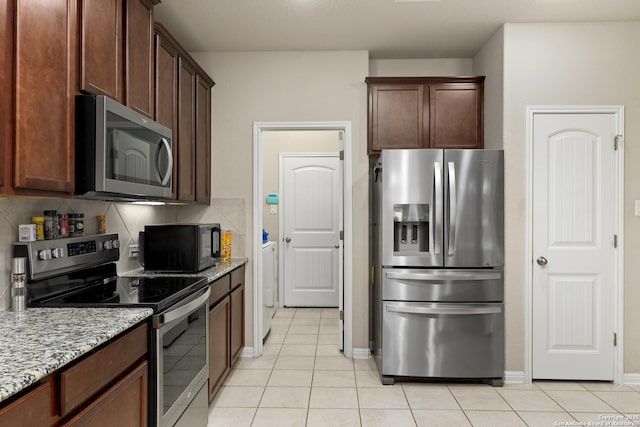 kitchen featuring stainless steel appliances, tasteful backsplash, light stone countertops, and light tile patterned flooring