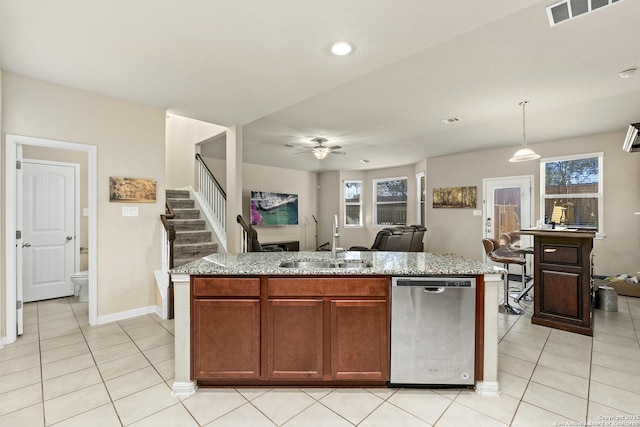 kitchen with light tile patterned flooring, sink, stainless steel dishwasher, pendant lighting, and a kitchen island with sink