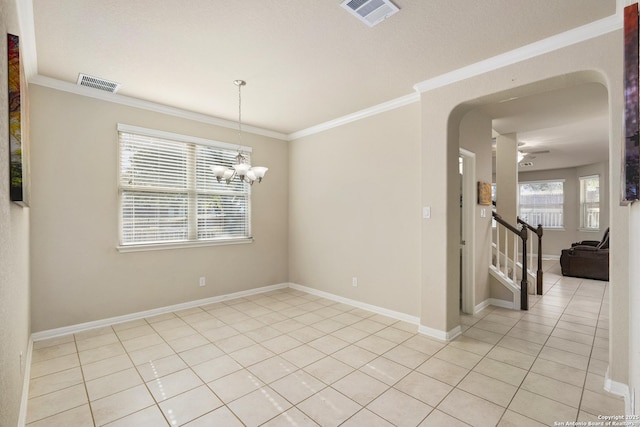 empty room featuring light tile patterned floors, crown molding, a notable chandelier, and a healthy amount of sunlight