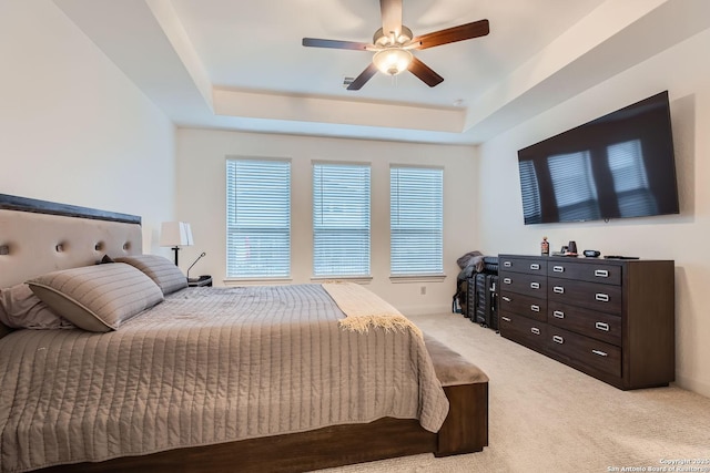 bedroom featuring a tray ceiling, a ceiling fan, and light carpet