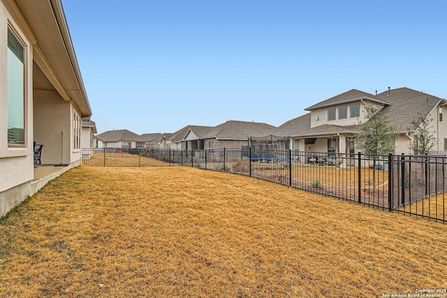 view of yard with a fenced backyard, a residential view, and a trampoline