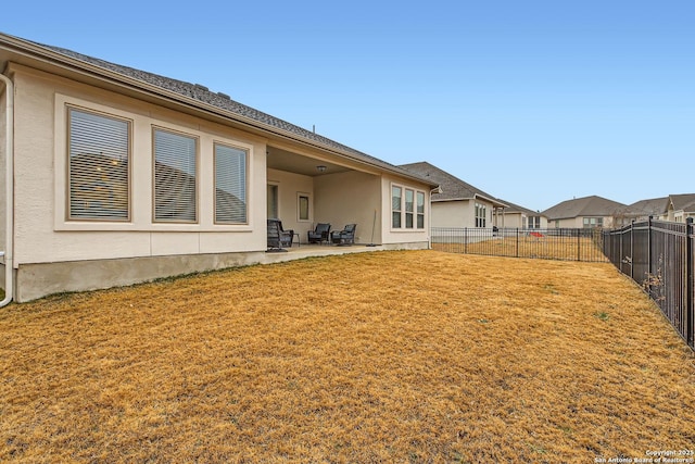 rear view of property featuring a patio area, a lawn, a fenced backyard, and stucco siding