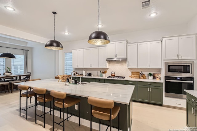 kitchen with visible vents, a sink, under cabinet range hood, stainless steel appliances, and green cabinetry