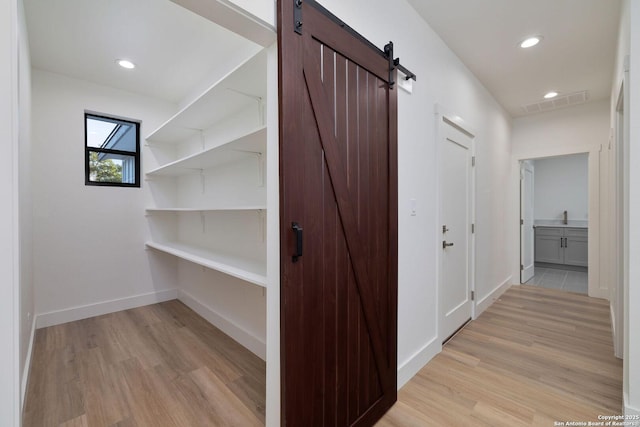 hallway with a barn door, sink, and light hardwood / wood-style floors