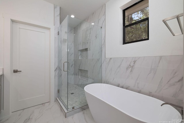 bathroom with vanity, shower with separate bathtub, and tile walls