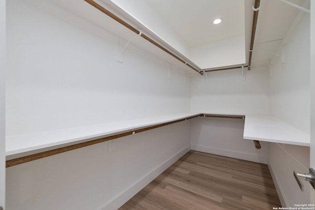 walk in closet featuring built in desk and light hardwood / wood-style flooring