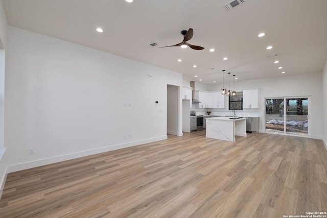 kitchen featuring ceiling fan, light hardwood / wood-style floors, white cabinets, a kitchen island, and decorative light fixtures