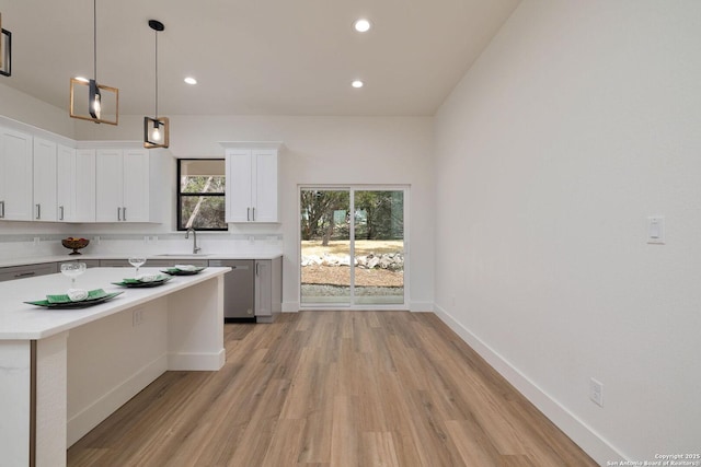 kitchen with decorative light fixtures, stainless steel dishwasher, a center island, and white cabinets