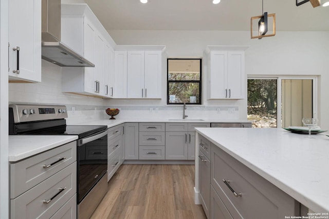 kitchen with pendant lighting, sink, gray cabinetry, electric range, and wall chimney range hood