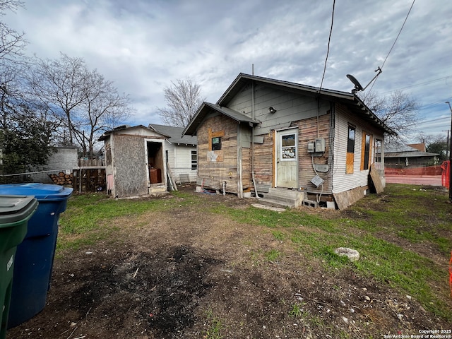 rear view of house with a yard and a storage unit