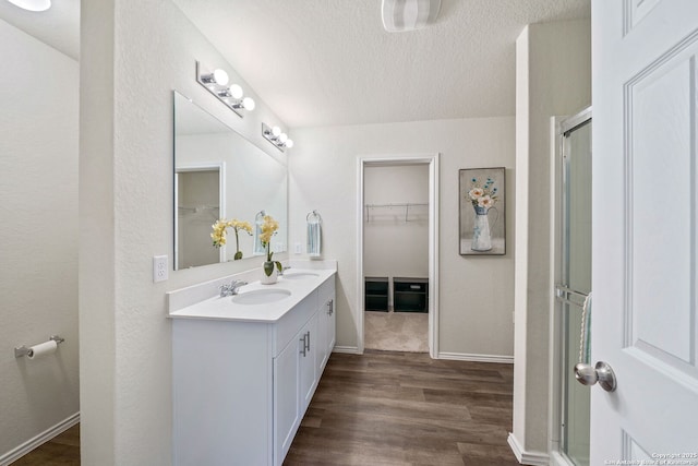 bathroom with vanity, a shower with shower door, hardwood / wood-style floors, and a textured ceiling