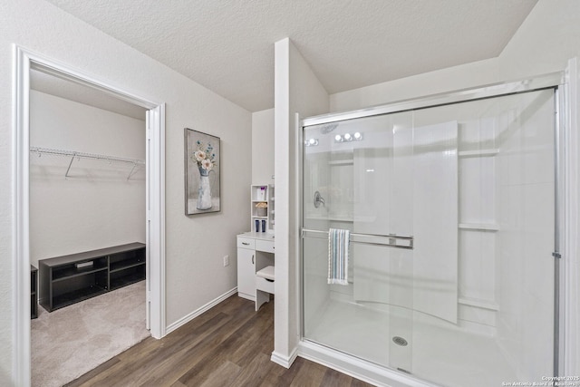 bathroom with hardwood / wood-style flooring, a textured ceiling, and a shower with shower door