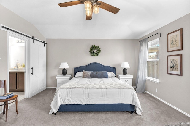 bedroom featuring vaulted ceiling, light colored carpet, ceiling fan, a barn door, and ensuite bath