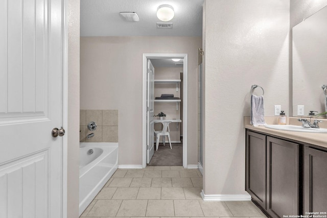 bathroom featuring tile patterned floors, vanity, a bath, and a textured ceiling