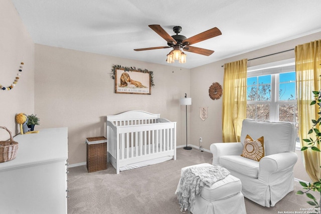 bedroom with light carpet, a crib, and ceiling fan