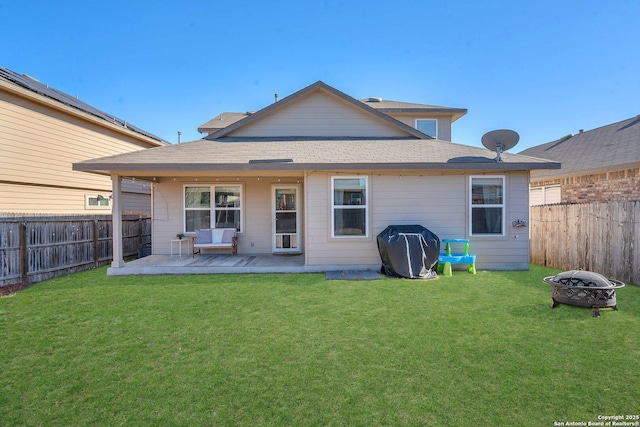 rear view of property featuring an outdoor fire pit and a yard