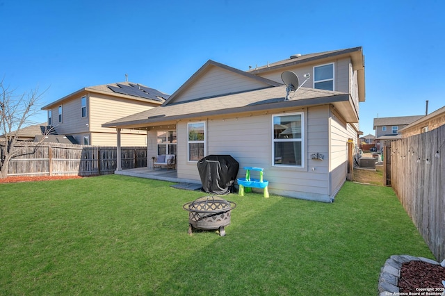 rear view of house featuring a fire pit and a lawn