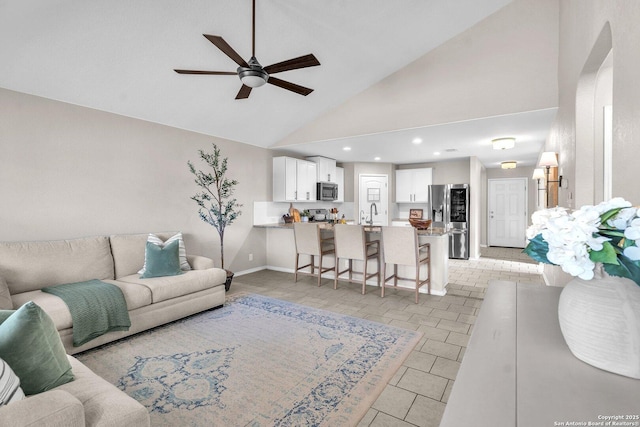 living room featuring light tile patterned flooring, high vaulted ceiling, sink, and ceiling fan