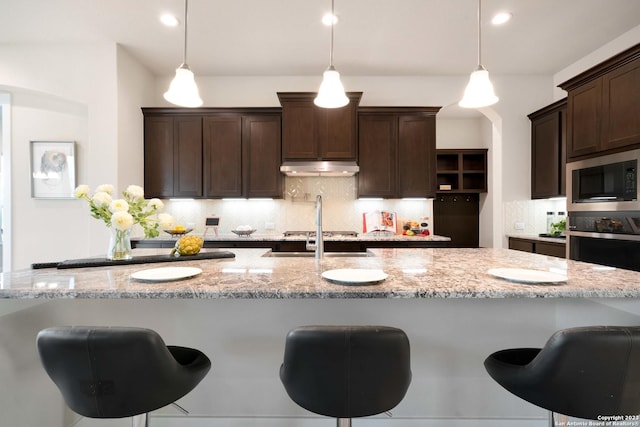 kitchen with built in microwave, hanging light fixtures, and a kitchen breakfast bar