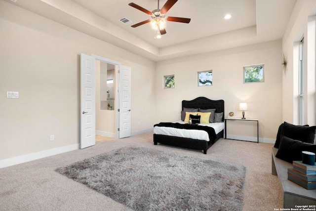 bedroom with ceiling fan, a raised ceiling, and carpet floors