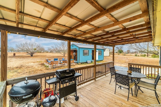 wooden deck with a storage shed, a grill, and a rural view